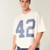 Camiseta de futebol americano com estampa gráfica, estilo universitário, folgada e pesada