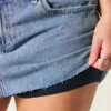 Mini-saia-calça de ganga curvilínea de cintura baixa e lavagem média Mini-saia-calça de ganga curvilínea de cintura baixa e lavagem média